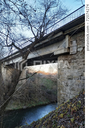 old stone bridge over a shallow river 72074274