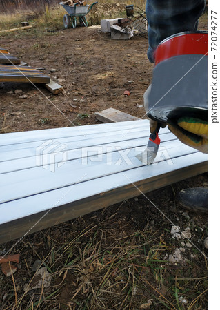 A man paints a white board with a paint brush A man paints a white board with a paint brush 72074277