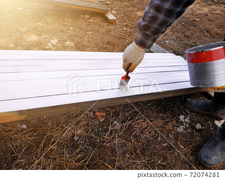 The process of painting pine wood panels with a brush and white paint 72074281