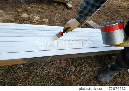 The process of painting pine wood panels with a brush and white paint 72074282