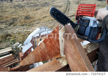 The builder saws on the roof of the chainsaw. Roof rafters. The builder saws on the roof of the chainsaw. Roof rafters. 72074327