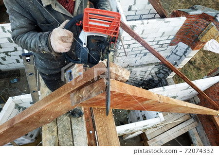 The builder saws on the roof of the chainsaw. Roof rafters. 72074332