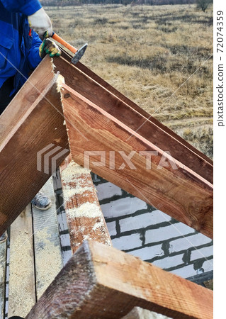 the worker shoots the rafters on the roof frame 72074359