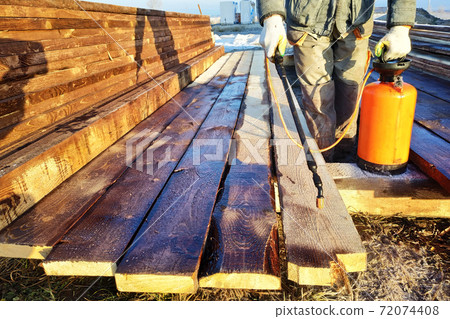 During the coloring of the boards, the worker uses a spray gun under pressure 72074408