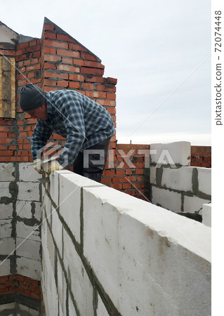 With the help of a glutinous solution, the worker builds a wall of gas blocks 72074448