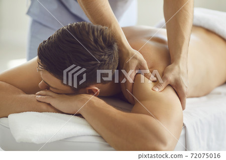 Young male client enjoying relaxing body massage in modern wellness or health center 72075016