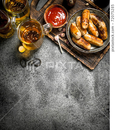Sausages in a frying pan with a cold beer. 72075285