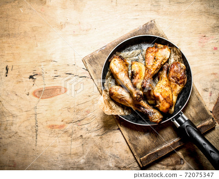 Fried chicken legs in frying pan. 72075347