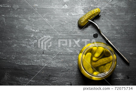 Pickled gherkins in a jar. 72075734