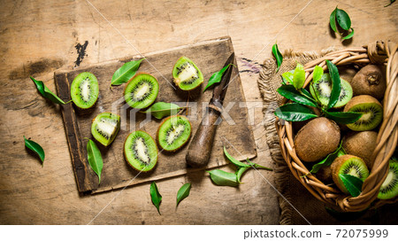 Fresh sliced kiwi with a knife and a full basket and leaves. Fresh sliced kiwi with a knife and a full basket and leaves. 72075999