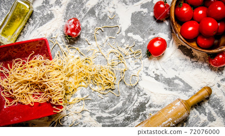 Noodles with tomatoes in a cup and rolling pin. Noodles with tomatoes in a cup and rolling pin. 72076000