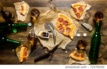 Pepperoni pizza and beer for four people. On a wooden table. Pepperoni pizza and beer for four people. On a wooden table. 72076090