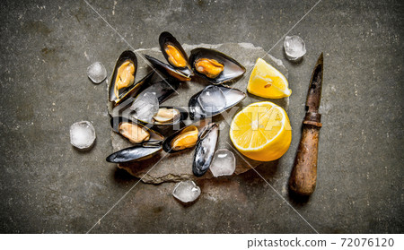 Fresh clams with lemon and ice on a stone stand. Fresh clams with lemon and ice on a stone stand. 72076120