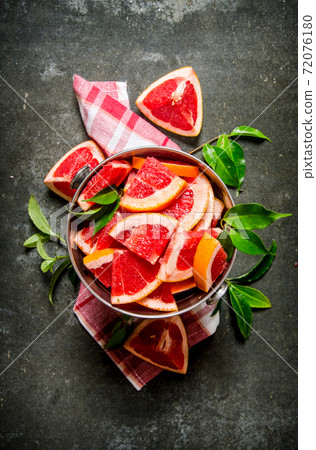 Cut the grapefruit with leaves in the bucket. 72076180