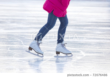 legs of a woman in blue jeans and white skates on an ice rink. hobbies and leisure. winter sports 72076486