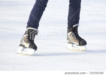 Legs of a man skating on an ice rink. Hobbies and sports. Vacations and winter activities Legs of a man skating on an ice rink. Hobbies and sports. Vacations and winter activities 72076599