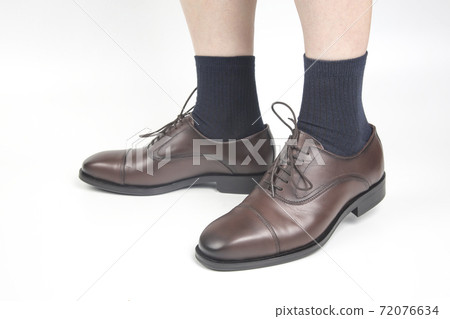 Male legs in socks and brown classic shoes on a white background 72076634