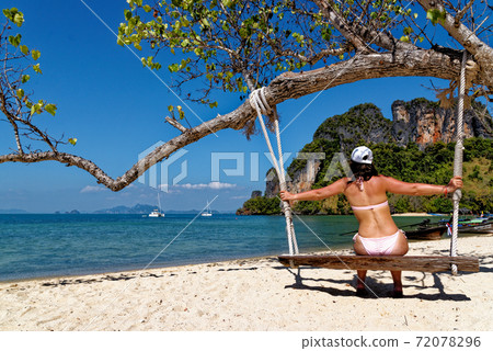 Young woman in wooden swing on the beach Young woman in wooden swing on the beach 72078296