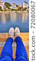 A relaxing time sitting on a quiet beach, a break, jeans and white sneakers 72080067