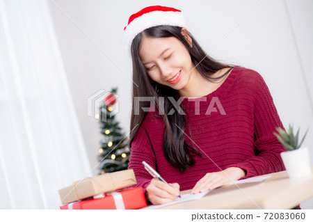 Young asian woman writing postcard in Christmas day at home, eve and celebrate. Young asian woman writing postcard in Christmas day at home, eve and celebrate. 72083060