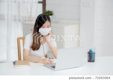 Young asian woman wearing headphone study online with e-learning on desk. 72083064