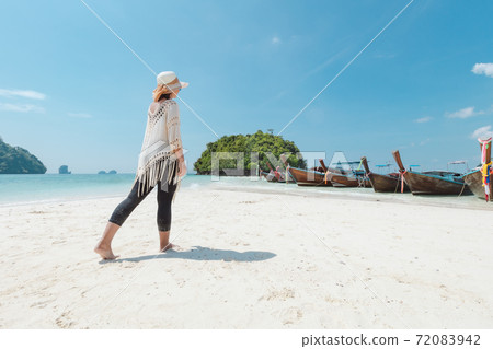 Asian woman walking on the beach and enjoying with beautiful nature in her vacation. Summer holidays and travel concept. Travelling in Thailand. Asian woman walking on the beach and enjoying with beautiful nature in her vacation. Summer holidays and travel concept. Travelling in Thailand. 72083942