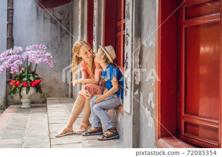 tourists mom and son on background of Temple Ngoc Son in Hanoi, Vietnam.Temple of Literature is also called temple of Confucius. Vietnam reopens after coronavirus quarantine COVID 19 tourists mom and son on background of Temple Ngoc Son in Hanoi, Vietnam.Temple of Literature is also called temple of Confucius. Vietnam reopens after coronavirus quarantine COVID 19 72085354