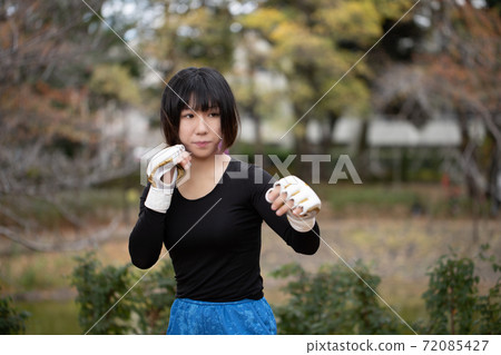 Woman in fighting pose in the park 72085427