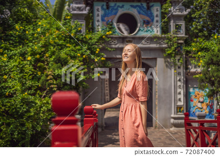 Caucasian woman traveler on background of Red Bridge in public park garden with trees and reflection in the middle of Hoan Kiem Lake in Downtown Hanoi. Vietnam reopens after coronavirus quarantine Caucasian woman traveler on background of Red Bridge in public park garden with trees and reflection in the middle of Hoan Kiem Lake in Downtown Hanoi. Vietnam reopens after coronavirus quarantine 72087400