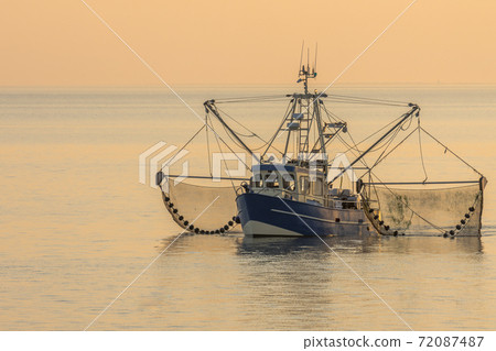 Fishing trawler with trawl nets at sunset, Buesum, North Sea, Schleswig-Holstein, Germany 72087487