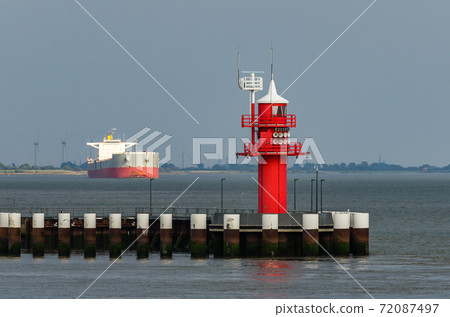Red lighthouse with cargo ship in background, Brunsbuettel, Schleswig-Holstein, North Sea, Germany Red lighthouse with cargo ship in background, Brunsbuettel, Schleswig-Holstein, North Sea, Germany 72087497