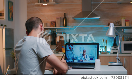 Man writing on notebook during online consultation 72088174