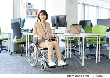 Portrait of a woman in a wheelchair smiling in the office Portrait of a woman in a wheelchair smiling in the office 72088285