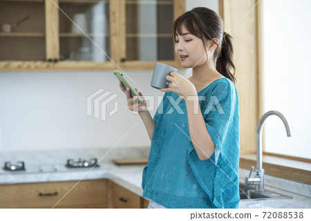 A young woman drinking coffee and using smartphone 72088538