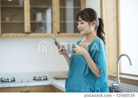 A young woman drinking coffee and using smartphone A young woman drinking coffee and using smartphone 72088539