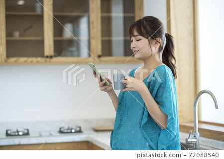 A young woman drinking coffee and using smartphone A young woman drinking coffee and using smartphone 72088540