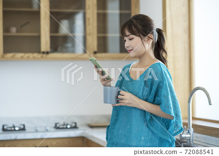 A young woman drinking coffee and using smartphone A young woman drinking coffee and using smartphone 72088541