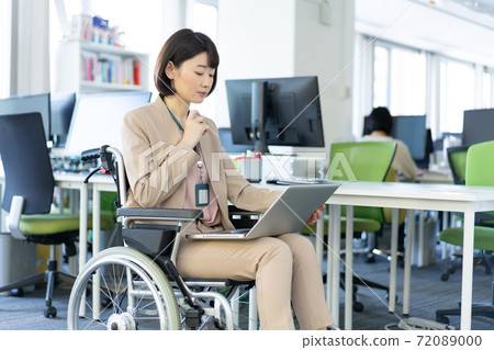 一名婦女的畫象輪椅的與她的在她的膝蓋的膝上型計算機一起使用在辦公室 一名婦女的畫象輪椅的與她的在她的膝蓋的膝上型計算機一起使用在辦公室 72089000