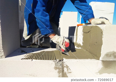 The master monitors the wall with gas blocks using glue and trowel 72089017