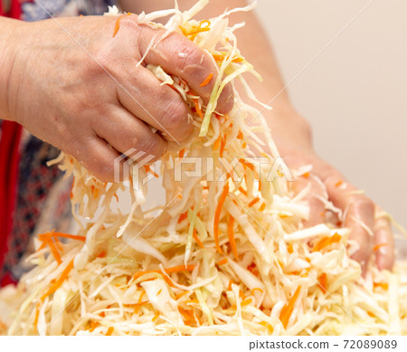 Woman salting cabbage with carrots in the kitchen 72089089