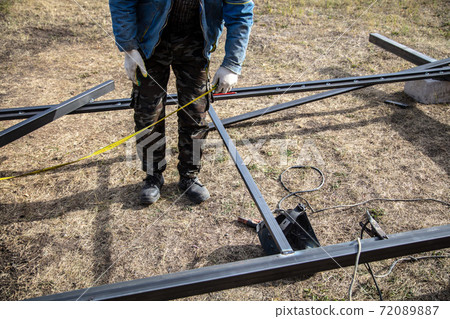 A worker measures metal at a construction site. Technology 72089887