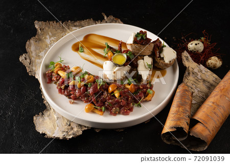 Veal tartare with pickled mushrooms and bruschetta with cream cheese, beef and quail egg. Cold raw meat dish with mushrooms. 72091039