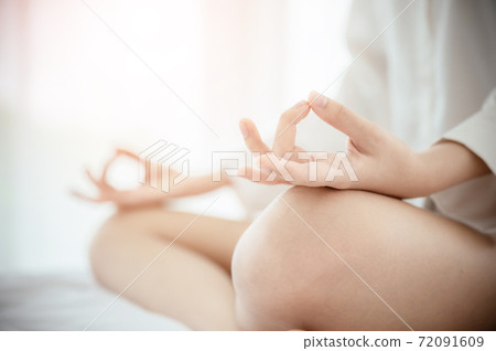 Closeup of young woman hand meditating on bed in bedroom at house Closeup of young woman hand meditating on bed in bedroom at house 72091609