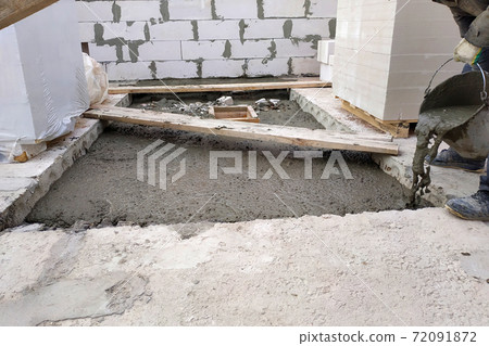 The builder pours a cement mortar slab between the floors of the house using a bucket The builder pours a cement mortar slab between the floors of the house using a bucket 72091872