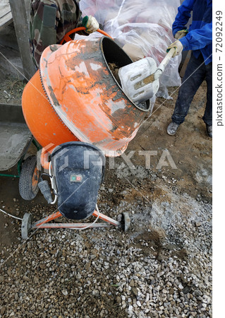 auxiliary worker develops a cement mortar in a concrete mixer at the construction of a country house 72092249