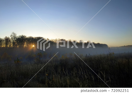 Beautiful thick fog sunrise Autumn Fall landscape over fields with treetops visible through fog 72092251