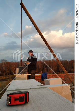 The master uses a glue for building a wall of blocks of white The master uses a glue for building a wall of blocks of white 72092393