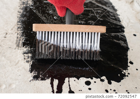 Roofer's hand in red mittens holding a brush 72092547