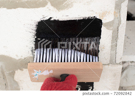 Roofer's hand in red mittens holding a brush 72092842