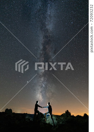Two persons shaking hands against long milky way Two persons shaking hands against long milky way 72093232